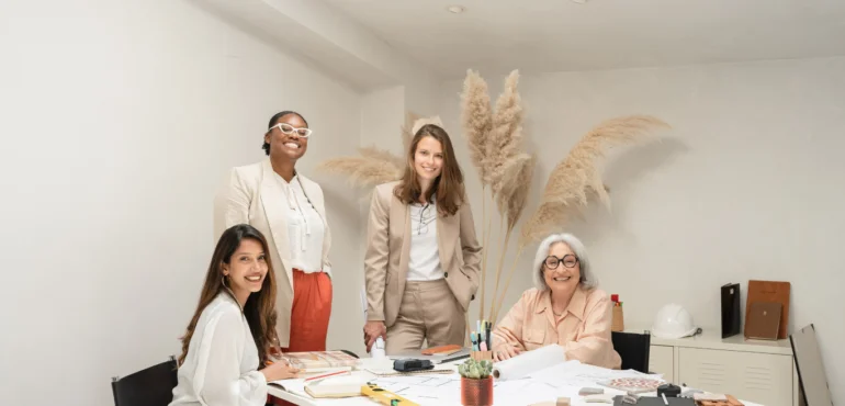 donne e lavoro. un gruppo di 4 donne di età ed etnie diverse riunite attorno a una scrivania.